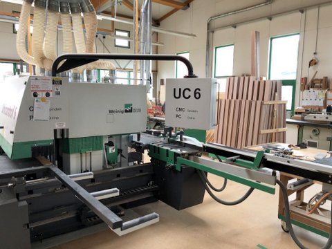 Holzbearbeitungsmaschine mit präzisem Schnitt, Holzplatten im Vordergrund.