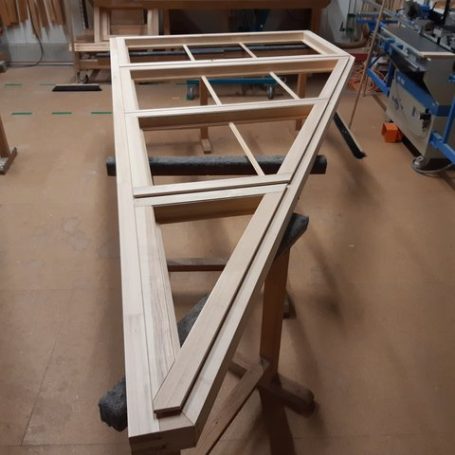 Ein Holzrahmen mit mehreren Rechtecken, auf einem Arbeitstisch in einer Werkstatt.